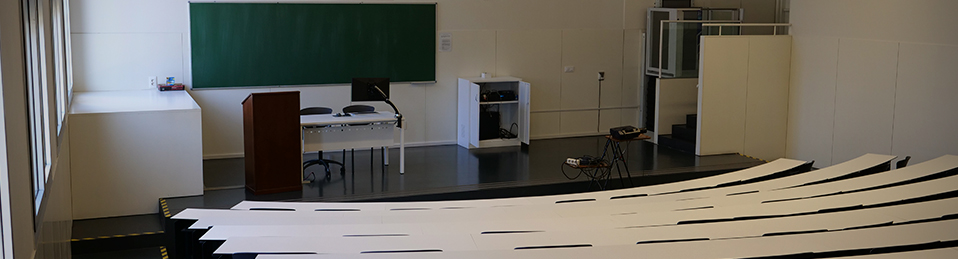 Imagen lateral de una de las aulas donde se imparten clases teóricas en la Facultad de Medicina. El aula cuenta con diverso equipamiento como un proyector o atriles